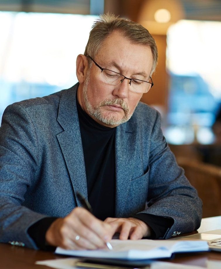 Older man writing business ideas in a book