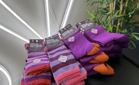 Roadmap MBA celebrating Purple Sock Day with 24 pairs of bright purple socks shown on a small black table
