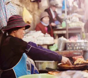 A lady cooking chicken at a market stall in Thailand running her own business