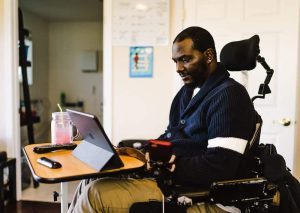 A man in a wheelchair using a iPad resting on a desk to use the Roadmap MBA