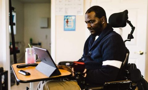 A man in a wheelchair using a iPad resting on a desk to use the Roadmap MBA