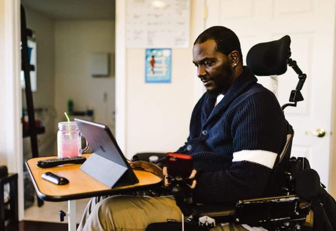 A man in a wheelchair using a iPad resting on a desk to use the Roadmap MBA