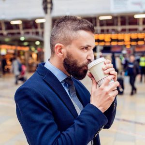 A smart professional man in a train station holding a coffee