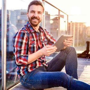 Man sitting on an outside balcony using an iPad.